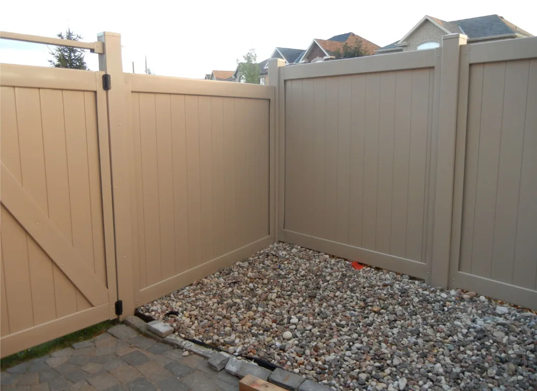 Low-maintenance vinyl privacy fence and gate with a gravel border in an Ottawa yard.