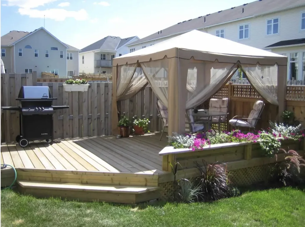 Ottawa backyard with a wood deck, gazebo and privacy fencing designed as one outdoor space.